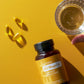 Bottle of Eterra EO Mega+ on a yellow background with capsules and a glass.
